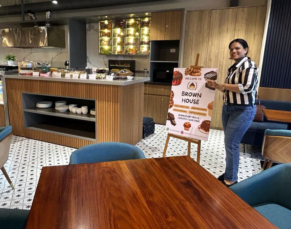 Neha beside the Brown House standee at an office centre café